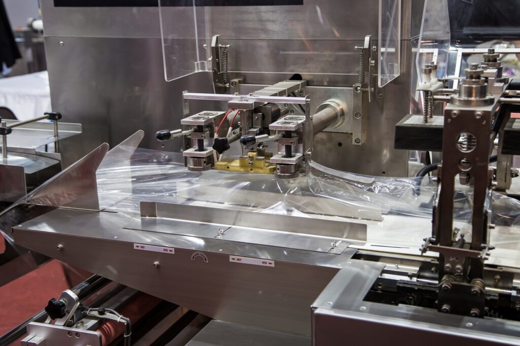 Nowoczesna maszyna pakująca typu flow pack producenta Tarpak pracująca w zakładzie produkcyjnym.